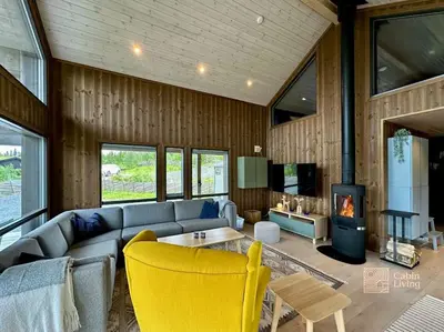 a living room with a couch and a fireplace at Modern cabin Skeikampen with ski-in out cross country trails & great view in Aulstad