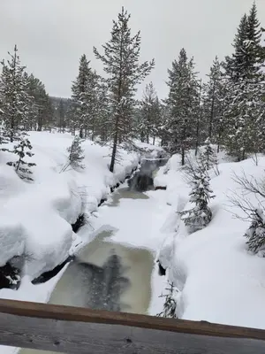 a stream in a snow covered field with trees at Coazy cabin with sauna in Trysil