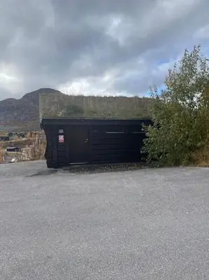 a large black garage with a hill in the background at Hovden Alpin Lodge! Ski in out in Hovden