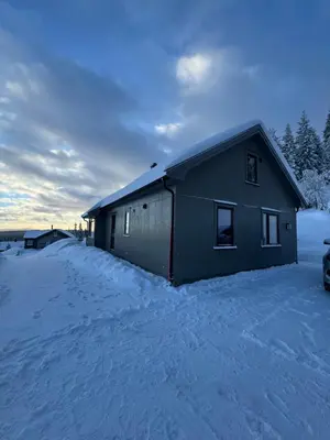 a building in the snow with a car parked next to it at Ny moderne hytte i Aust-Torpa in Aust-Torpa
