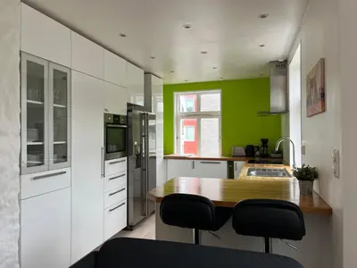 a kitchen with white cabinets and a wooden table at Bendixens vei 57 in Bergen