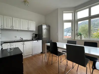 a kitchen with white cabinets and a table and chairs at Bendixens vei 57 in Bergen