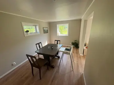 a dining room with a table and chairs and two windows at Hus i Syvde in Sylte