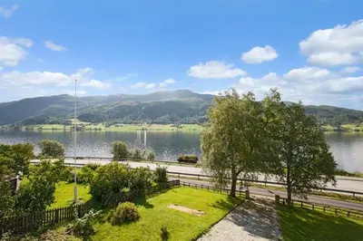 a view of a lake with a fence and trees at Voss- Myrkdalen Lodge in Vossestrand