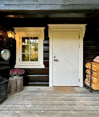 a wooden house with a white door and a window at Log cabin in Hafjell with ski in ski out, sauna and view in Hafjell