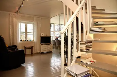 a living room with a staircase with books at Villa Paradiso, Cathedral View & Parking in Trondheim