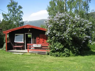 a small cabin with a bench and a tree at Kvila Hytteutleie in Garmo