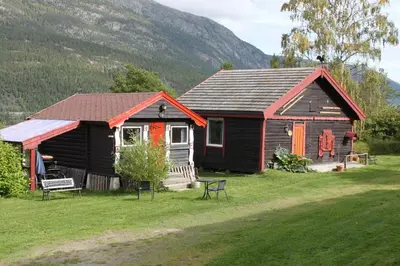 a small house in a field with a mountain at Kvila Hytteutleie in Garmo