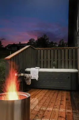 a hot tub on a deck next to a fire pit at Moderne hytte på Fjellsætra med Jacuzzi in Sykkylven