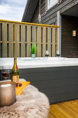 a bottle of wine and two wine glasses on a deck at Moderne hytte på Fjellsætra med Jacuzzi in Sykkylven
