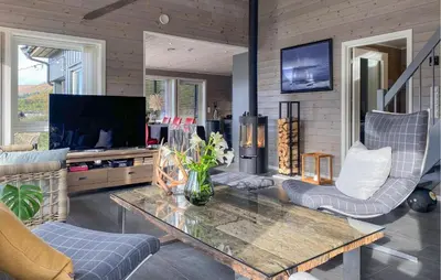 a living room with a table and chairs and a tv at 3 Bedroom Awesome Home In Nordfjordeid in Nordfjordeid