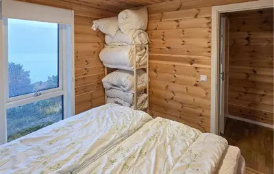 a bedroom with a stack of pillows on a bed at 2 Bedroom Lovely Home In Bjordal in Hogvær