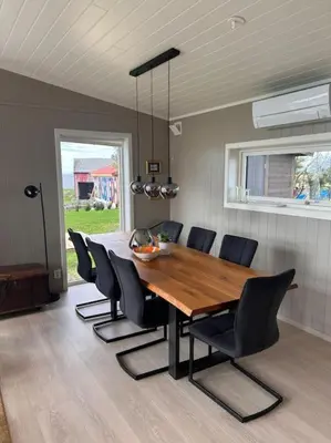 a dining room with a wooden table and chairs at Hytte v Farstadsanden Anders sandvigsvei 9 in Julshamn