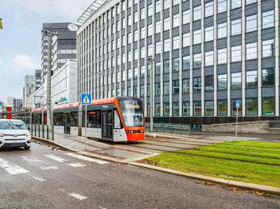 a bus driving past a tall building in a city at Stor leilighet i Bergen sentrum! in Bergen