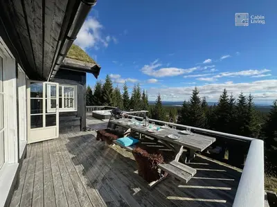 a deck with a table and benches on a house at Luxury cabin Sjusjøen with hot tub, ski in-out, fireplace & WiFi in Ringsaker