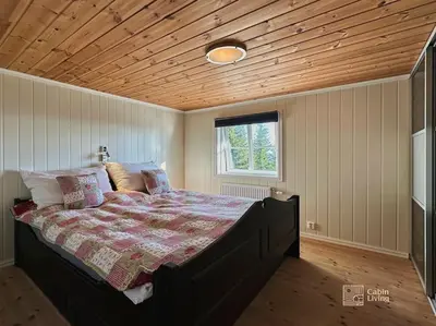 a bedroom with a bed with a wooden ceiling at Luxury cabin Sjusjøen with hot tub, ski in-out, fireplace & WiFi in Ringsaker