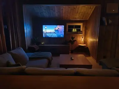 a living room with a couch and a flat screen tv at OlaHytta - Cozy cabin close to kvitfjell in Tromsnes