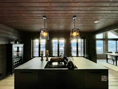 a kitchen with a sink and some lights and windows at Modern cabin at Høgevarde panoramic view, fireplace and EV station in Granheim