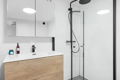 a white bathroom with a shower and a sink at Central stay apartment - 301 in Bergen
