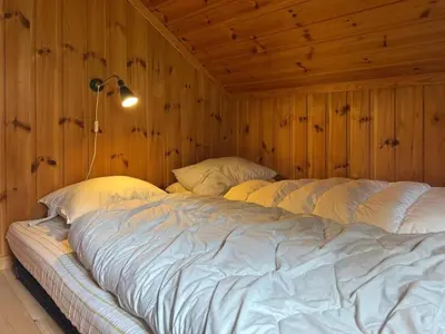 a bedroom with two beds in a wooden wall at Original Olympic cabin ski in out Hafjell in Hunder