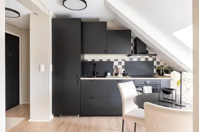 a kitchen with black cabinets and a table and chairs at Super Central renovated flat, next to Solsiden, Free Private Parking right outside ! in Trondheim