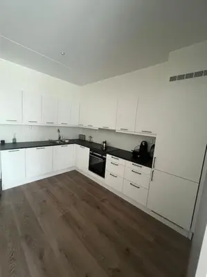 a kitchen with white cabinets and a wooden floor at SKI VM - Trondheim 2025 in Heimdal