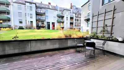two chairs and a table on a balcony with buildings at Stylish & Modern Apartment, in Centre, Free Parking spot ! in Trondheim