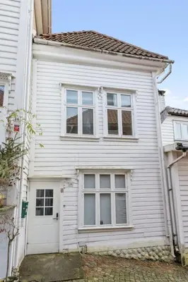 a white house with a door and three windows at Historisk hus i hjertet av byen in Bergen