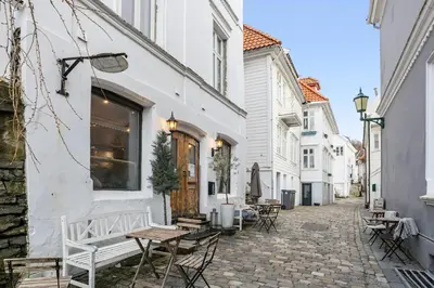 a cobblestone alley with tables and chairs on a building at Historisk hus i hjertet av byen in Bergen