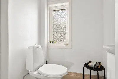 a white bathroom with a toilet and a window at Trolltunga Fjord View in Tokheim