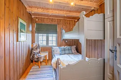 a bedroom with a bed in a wooden room at Tovebu Superior 9-sengshytte in Geilo