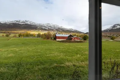 a window view of a field with a red barn at Cozy apartment close to the ski resort in Oppdal