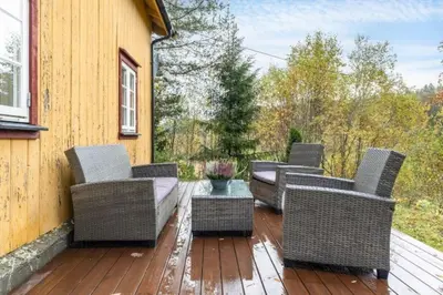 a patio with wicker chairs and a table on a deck at Rindalsskogen cabin in Løfald