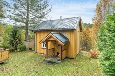 a small yellow shed with a roof in a yard at Rindalsskogen cabin in Løfald