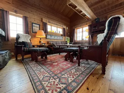 a living room with a piano and a rug at Familiehytte Med Peis Og Badstu I Sentrum in Beitostøl