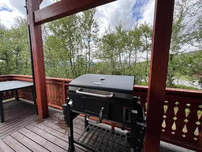 a grill sitting on a porch with a view of the woods at Familiehytte Med Peis Og Badstu I Sentrum in Beitostøl