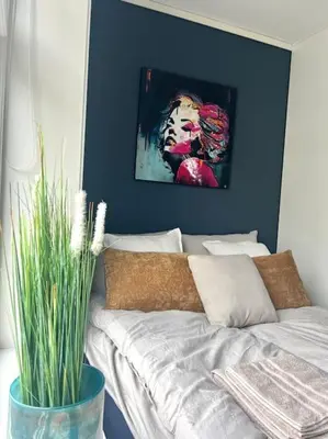 a bed in a room with a painting on the wall at Hellegata 5 - in the heart of Ålesund in Ålesund