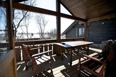 a wooden porch with a table and chairs on it at Koselig Sentral Eldre Hytte Med Peis in Beitostøl