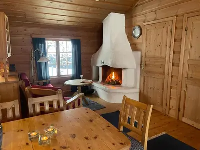 a living room with a fireplace in a log cabin at Koselig Sentral Eldre Hytte Med Peis in Beitostøl
