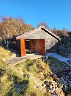 a small building with a wooden deck in a field at Cabin on an beautiful island with a sea view in Vinsternes