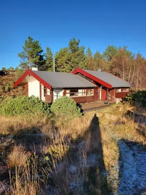 a large red and white house on a hill at Cabin on an beautiful island with a sea view in Vinsternes