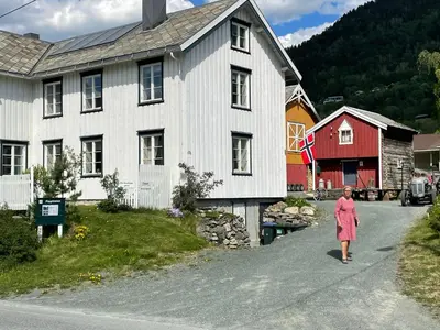 a woman walking down a road in front of a house at Ner-Grefstad gard in Kallstad