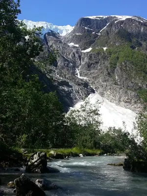 a river with snow on the side of a mountain at Bøyum Camping in Fjarland