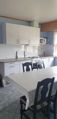 a kitchen with a table and chairs and white cabinets at Bøyum Camping in Fjarland