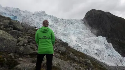 a woman standing on a mountain looking at a glacier at Bøyum Camping in Fjarland