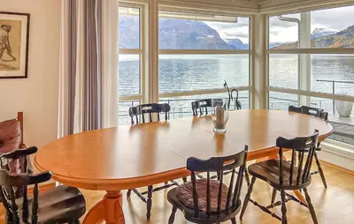 a dining room with a table and chairs and a large window at 4 Bedroom Awesome Home In Luster in Luster