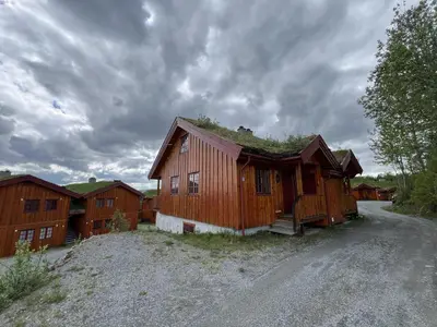 a barn with a grass roof on a dirt road at 3-Story Apartment Near Slopes With Sauna And Views in Beitostøl