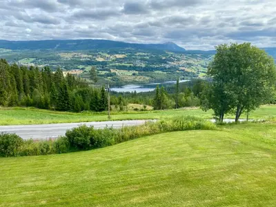 a field of grass with a road and a river at Leilighet i enebolig in Fagernes