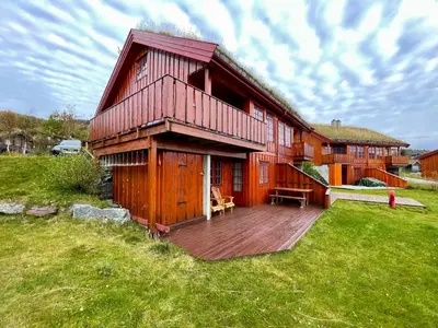 a large wooden house with a deck in a field at 3-Story Apartment Perfect For Up To 10 Guests in Beitostøl