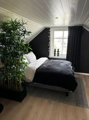 a bedroom with a black bed and a window at NY og moderne studioleilighet med elbil lading in Gjøvik